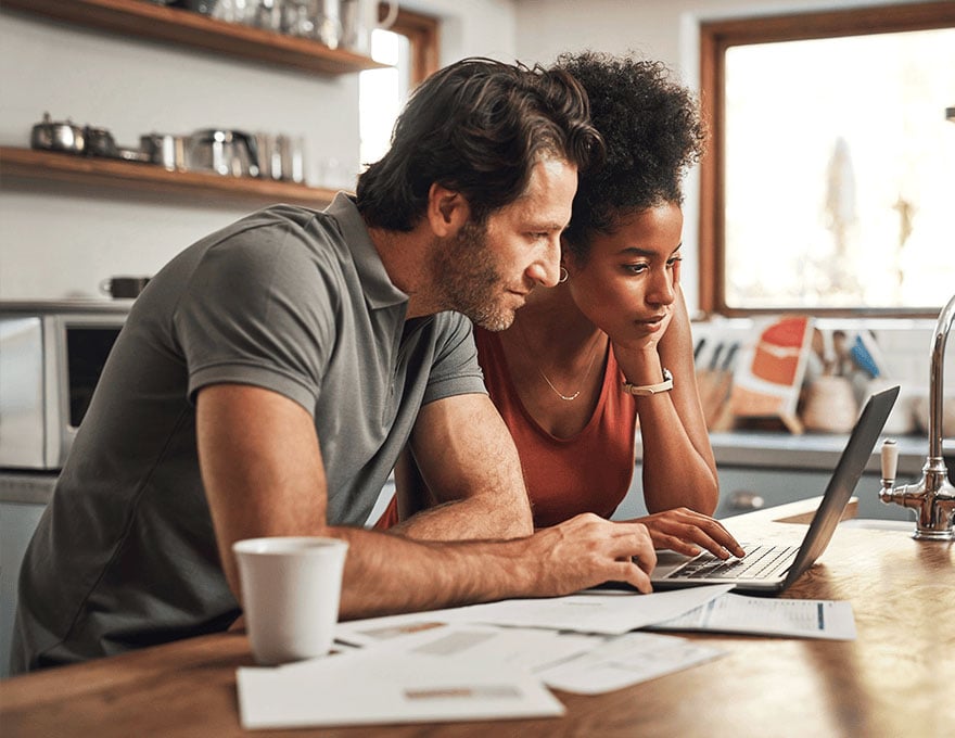 Couple-using-laptop-with-financial-planning-in-a-kitchen-with-documents