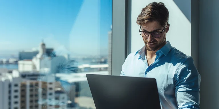 Investor standing by window with a laptop, learning why diversification is important.