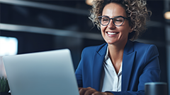 A worker smiling at a desk with a laptop