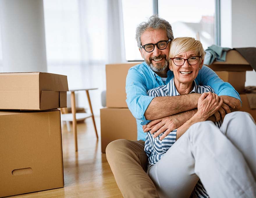 Mature-couple-hugging-while-moving-into-new-house