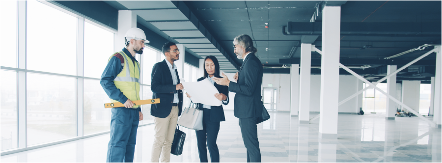 People studying blueprint indoors in modern commercial building