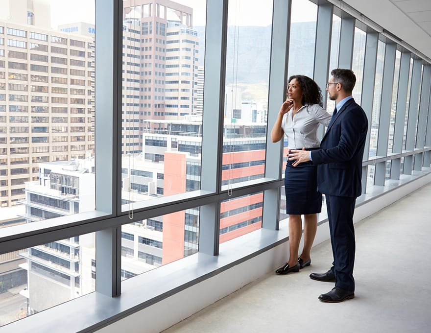 two-people-looking-out-of-window-of-tall-building
