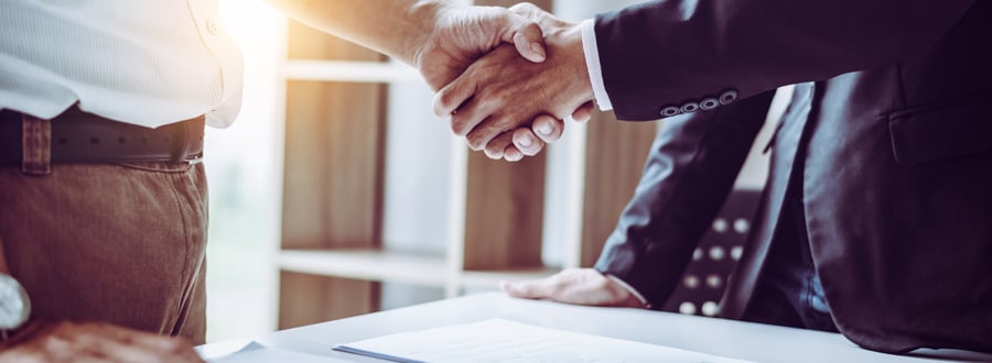 Two businesspeople shaking hands over a contract